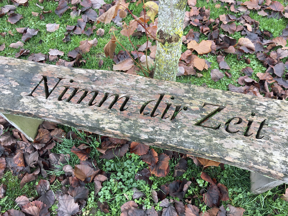 Eine Holzbank, auf der &laquo;Nimm dir Zeit&raquo; eingefr&auml;st ist.